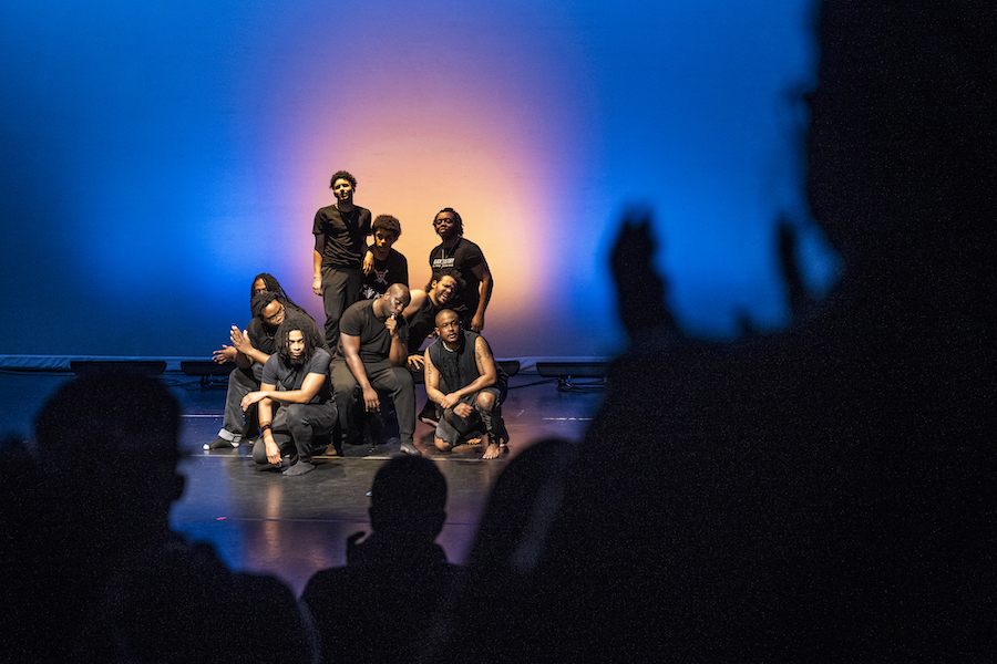 Group of Black men on stage with dark blue and yellow lighting