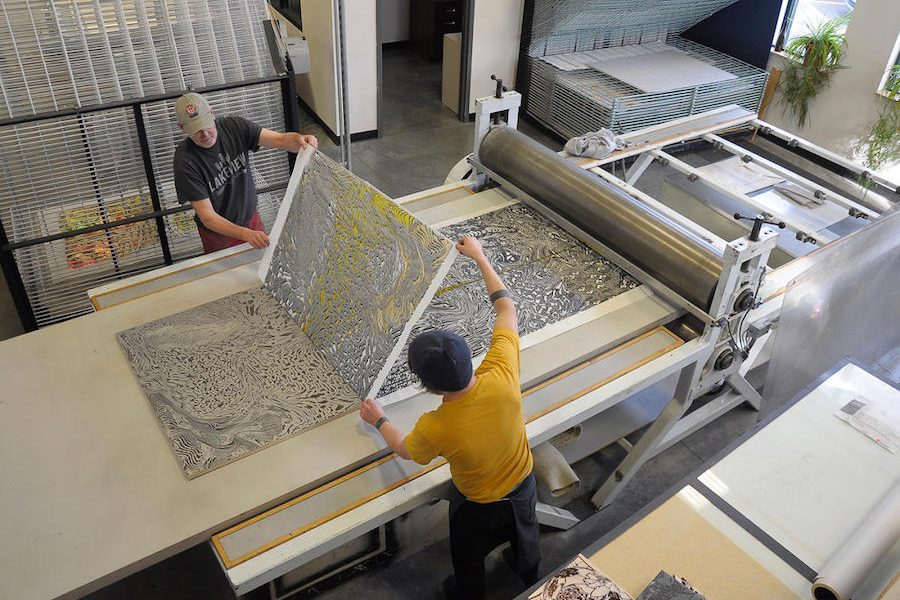 Two men operate a screenprinting press